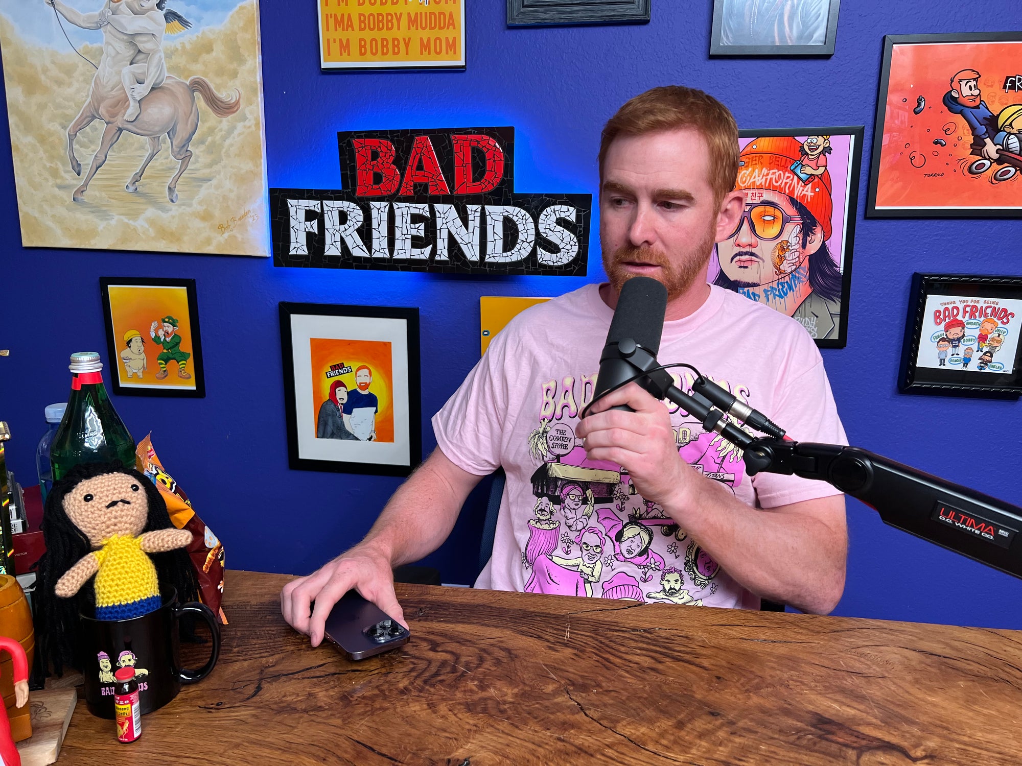 Andrew in his pink bad friends world shirt at his podcast chair